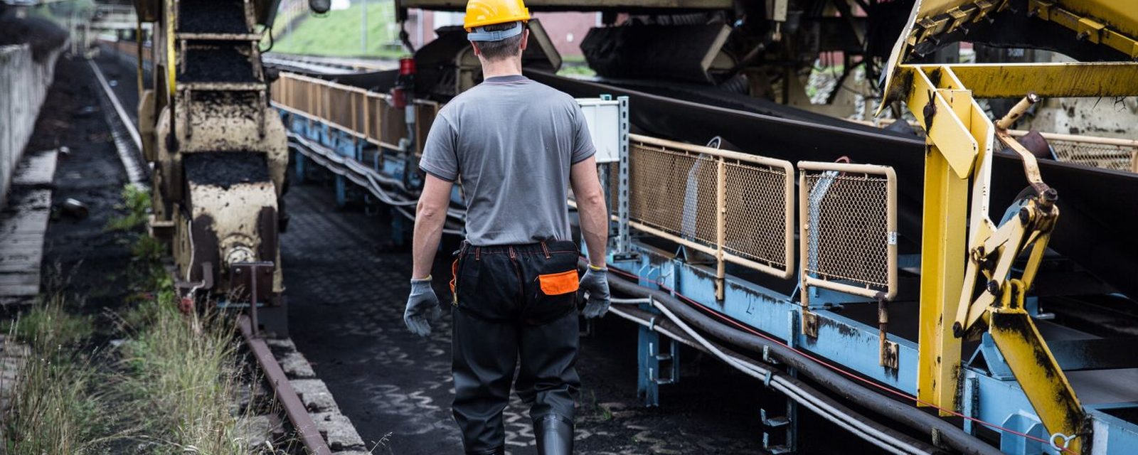 Trabalhador com capacete em área industrial de transportadores