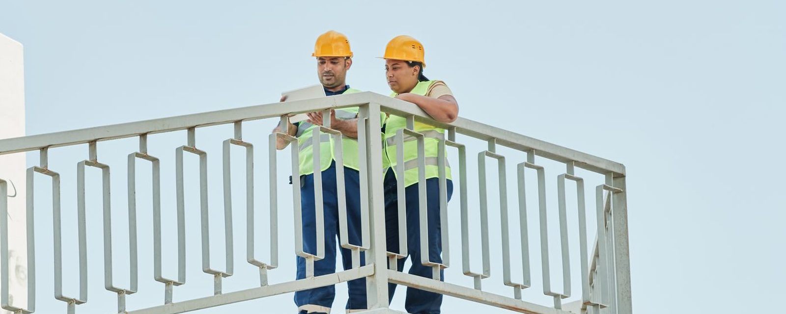 Dois técnicos com EPI inspecionando estrutura de concreto